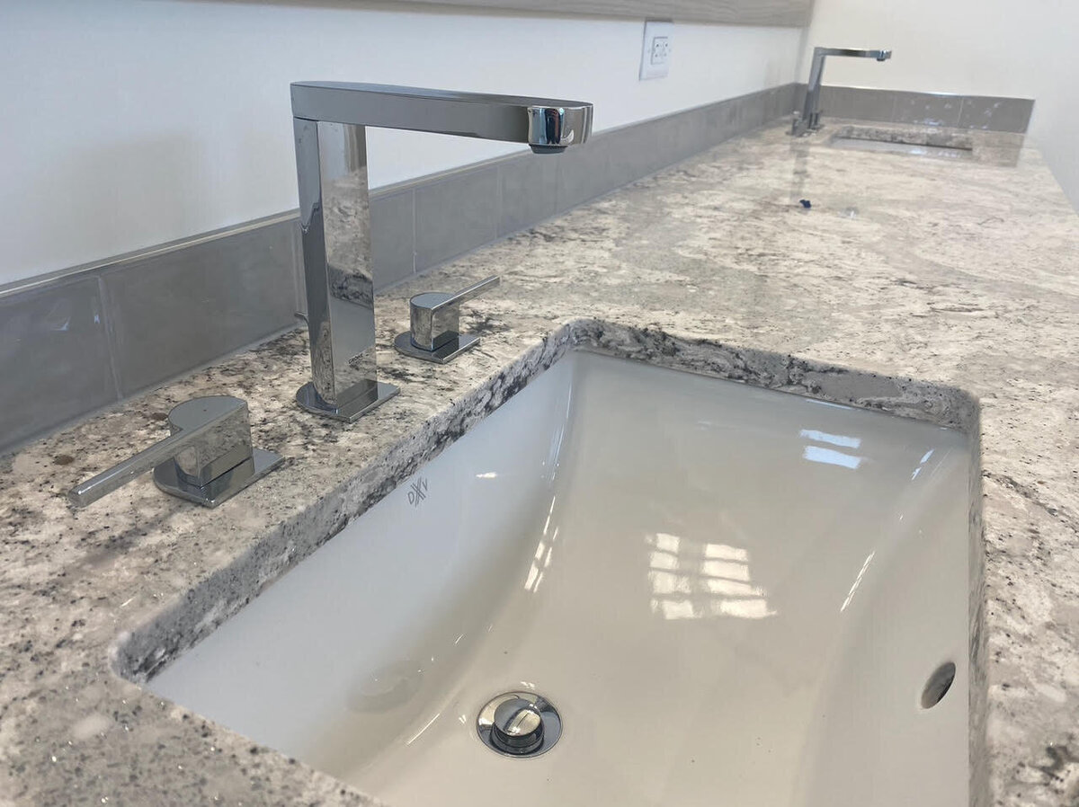 Custom bathroom vanity design with stone counters and stainless faucets.
