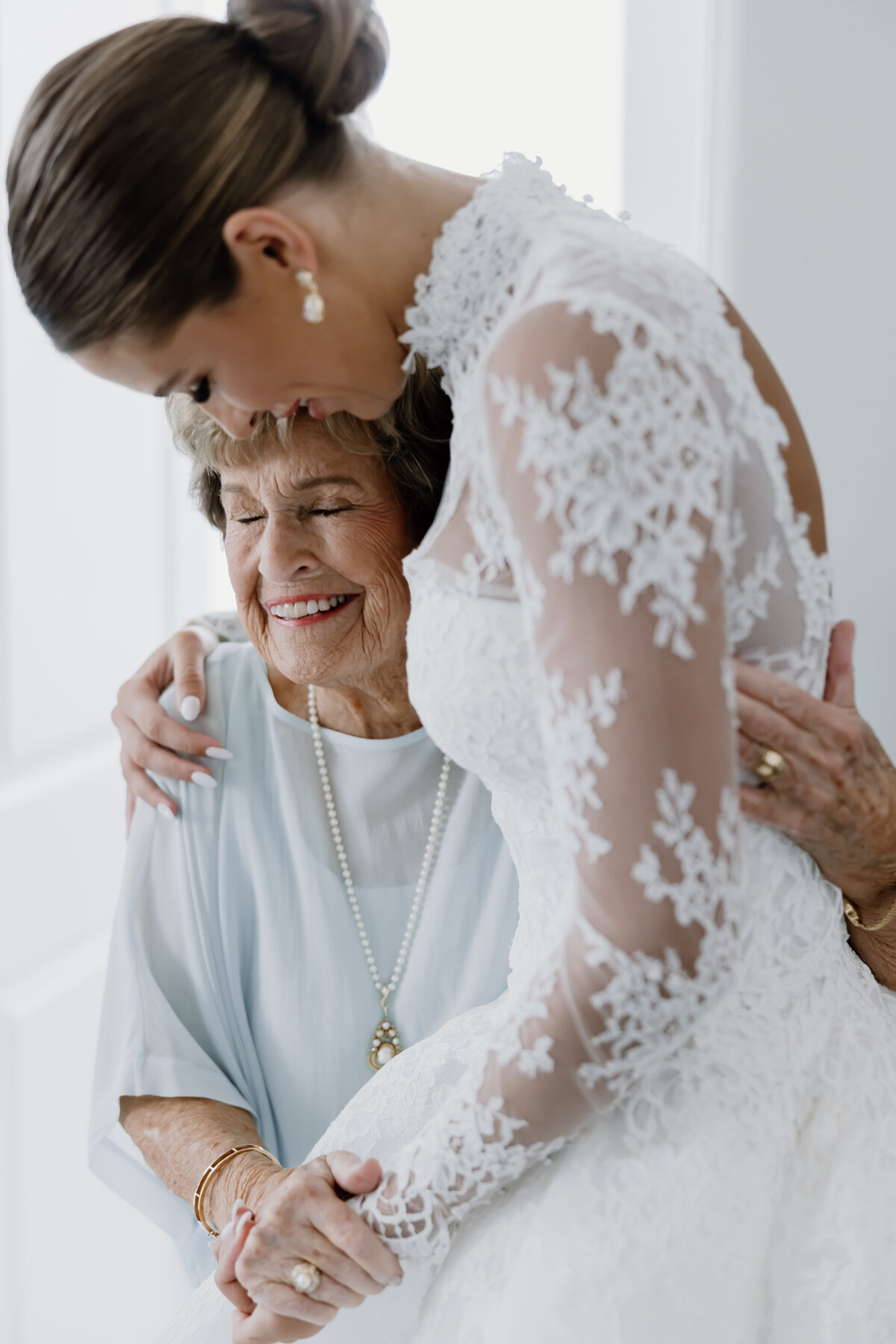Grandmother hugging her granddaughter bride in her wedding dress by Kansas City photographer Abbey Regnier.