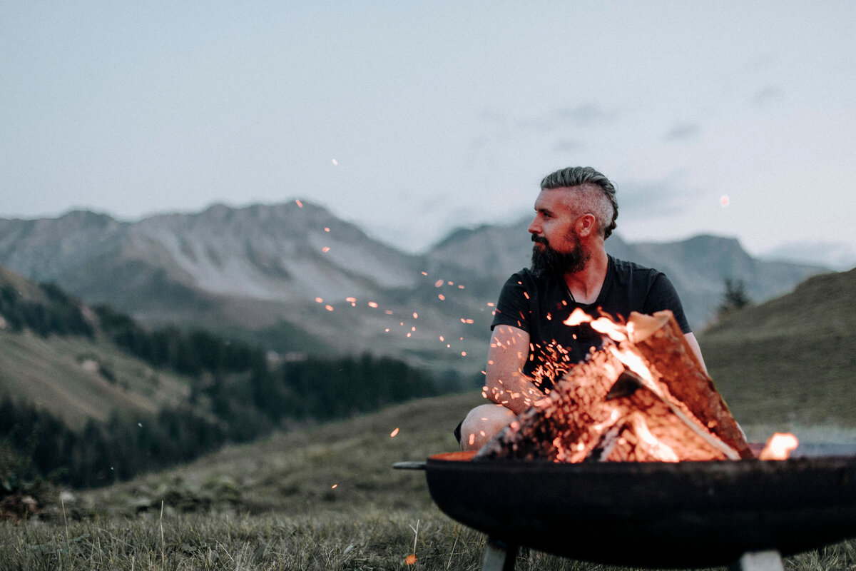 Alec in the swiss mountains by a fire.