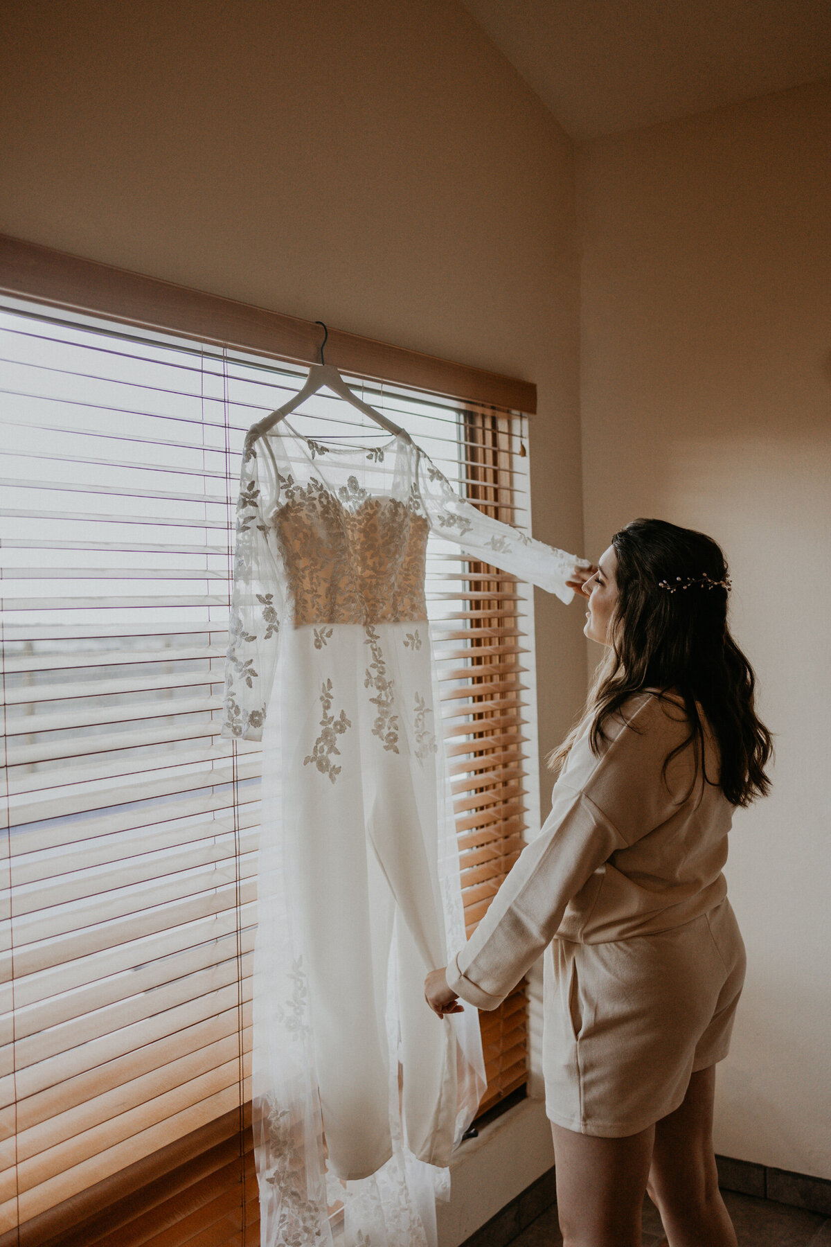 bride looking at her hanging lace jumpsuit before her ceremony