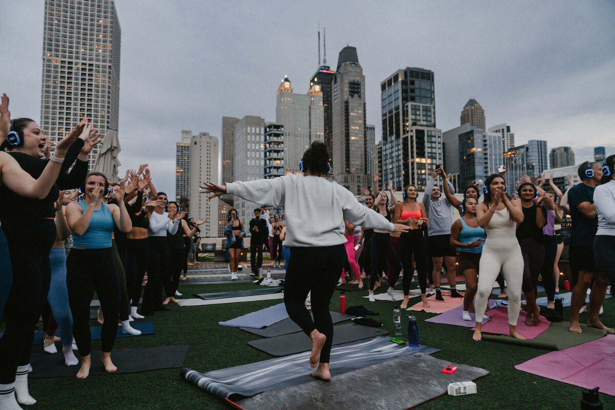 Group of people dancing on their yoga mats listening to music with headphones