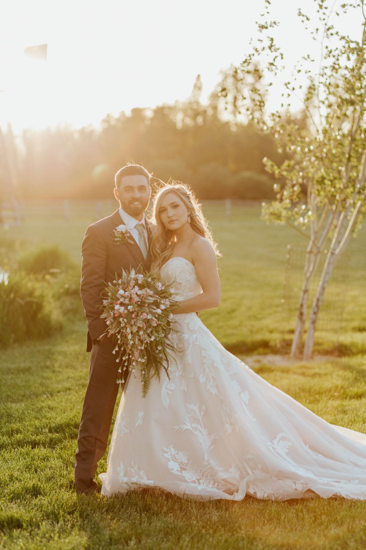 bride and groom posing in field