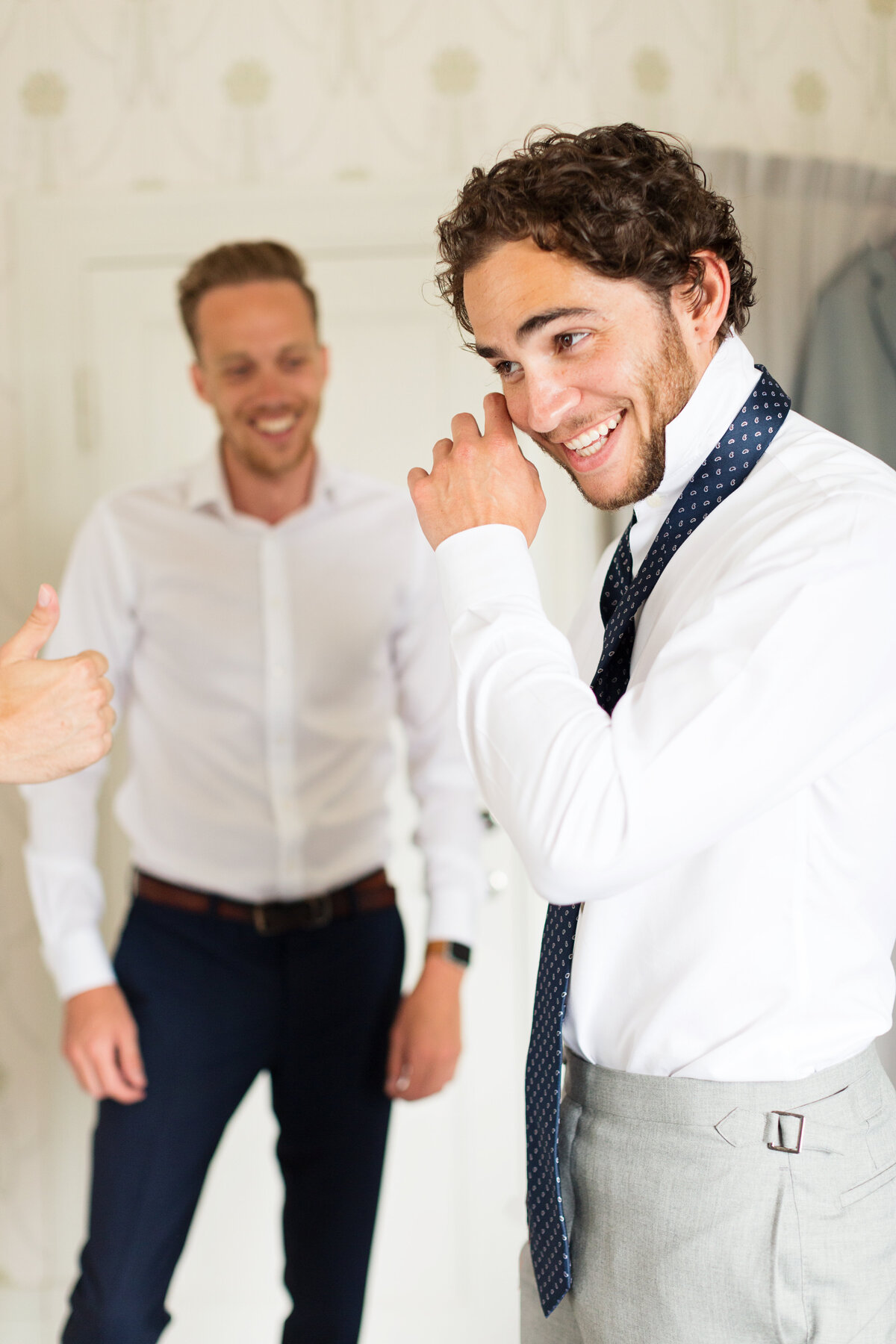 Brudgum skrattar när hans vänner knyter slipsen