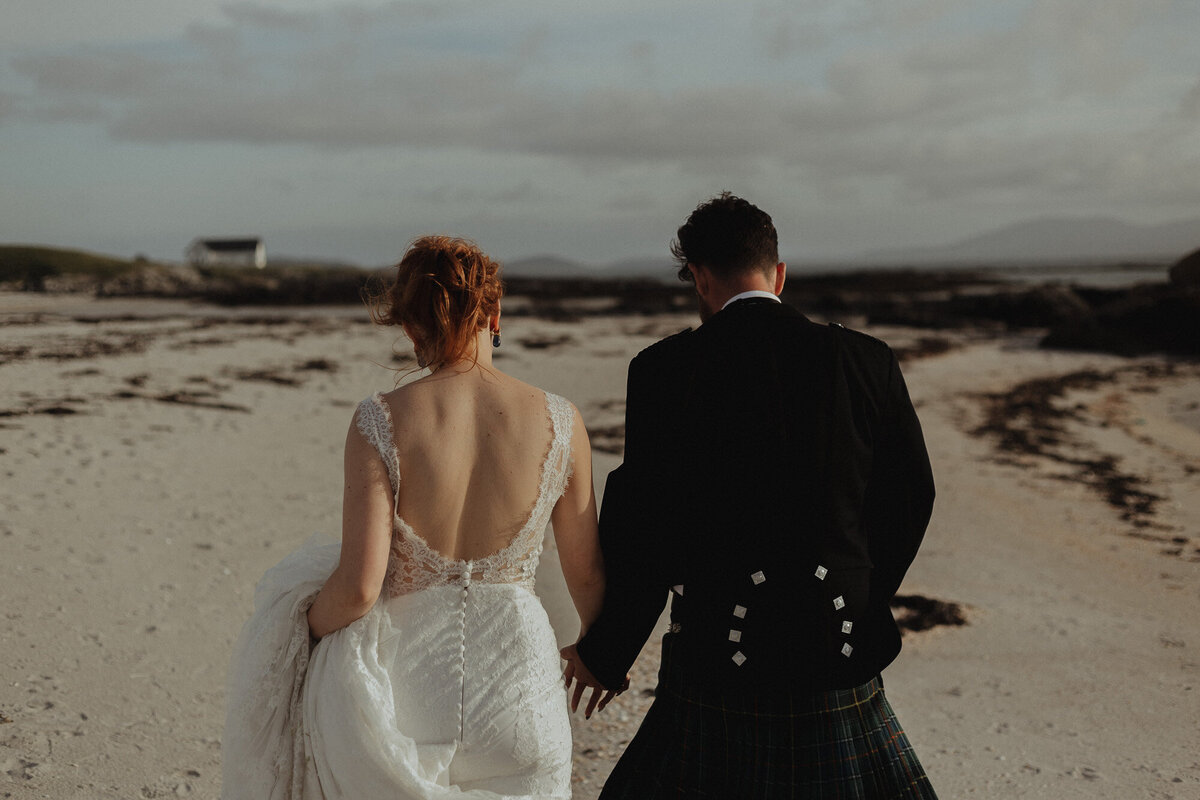 bride and groom walking holding hands on the beach