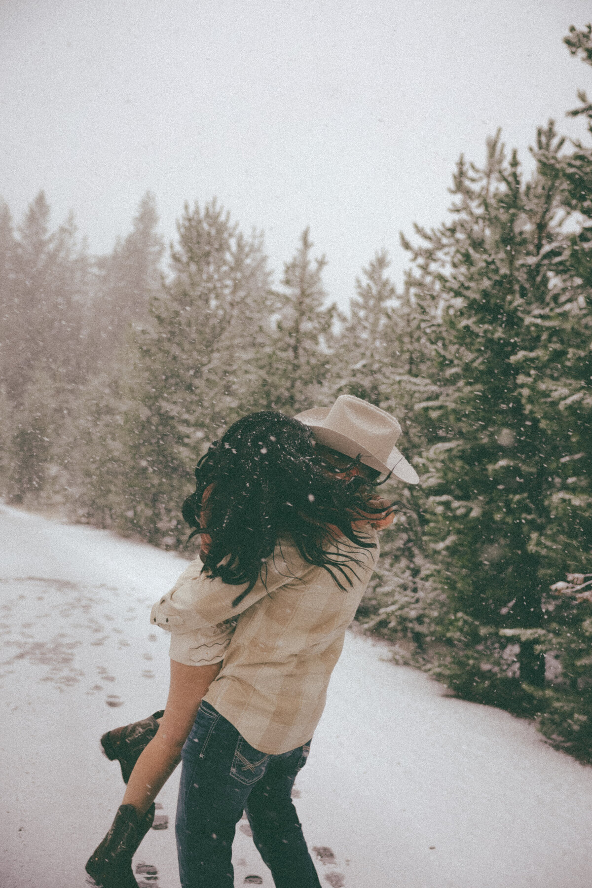 Playful Cowboy and Cowgirl Twirling in the Falling Snow Engagement Photos