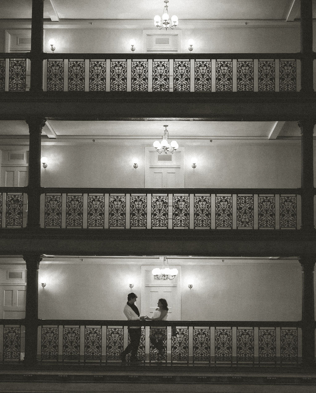 A couple standing on an indoor balcony of a hotel.