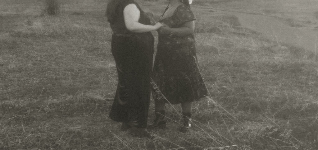 A couple holding hands in a grassy area.