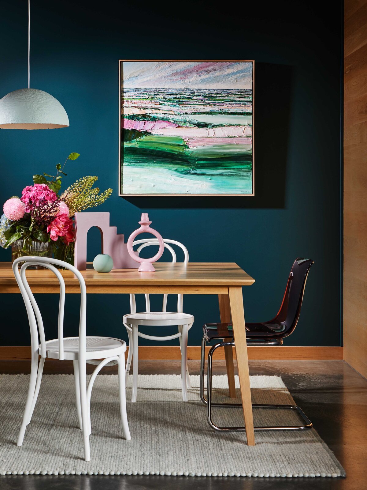 Contemporary dining room with navy feature wall, white chairs and pink artwork styled by Melbourne interior decorator