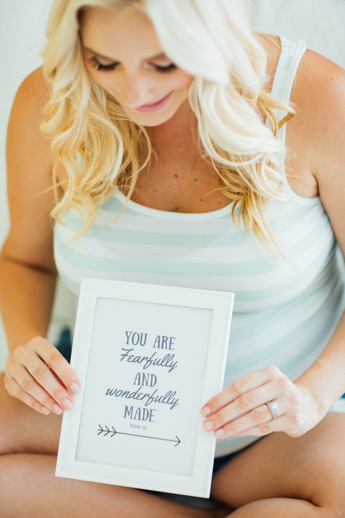 Mom to be holds a sign up during a maternity photo shoot so her child will read it in the future