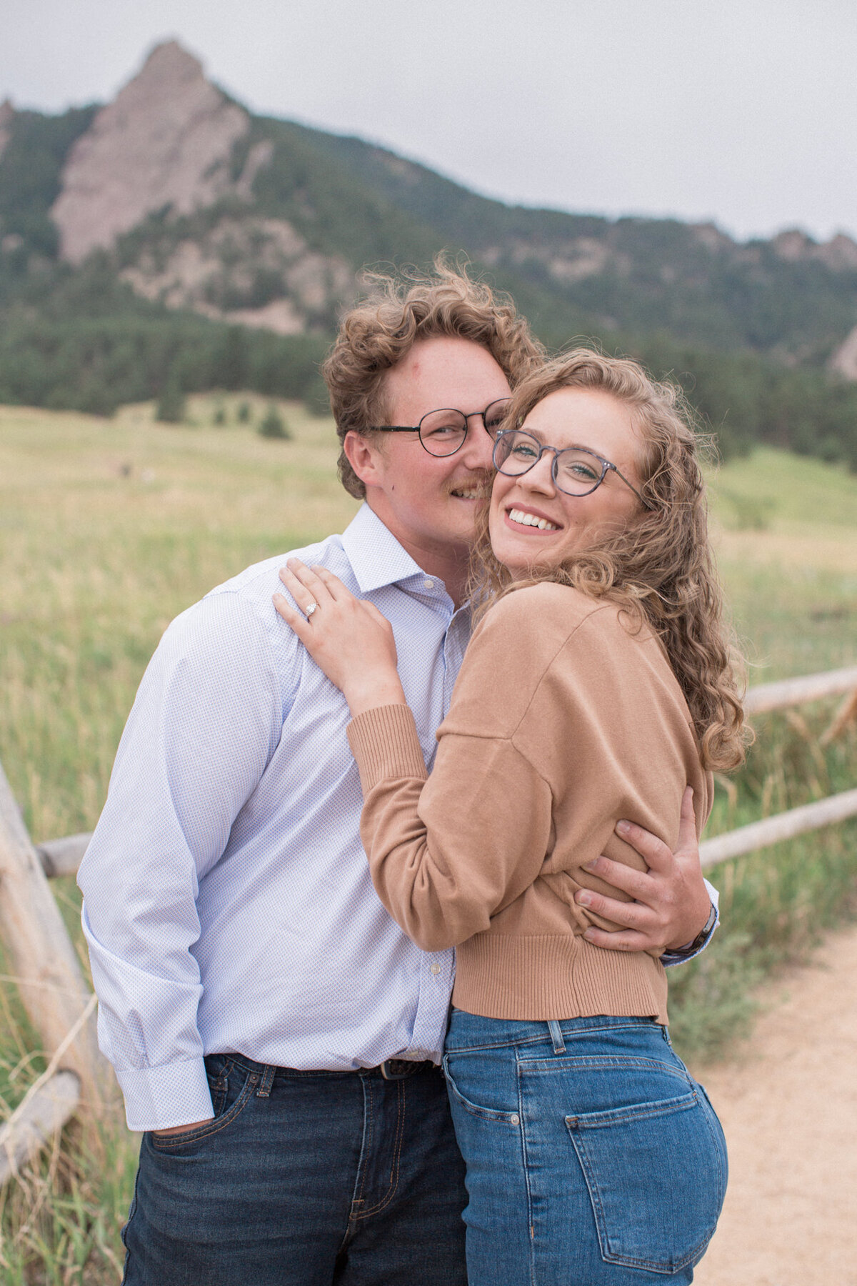 A couple embraces closely while smiling for the camera during their Boulder engagement photography session