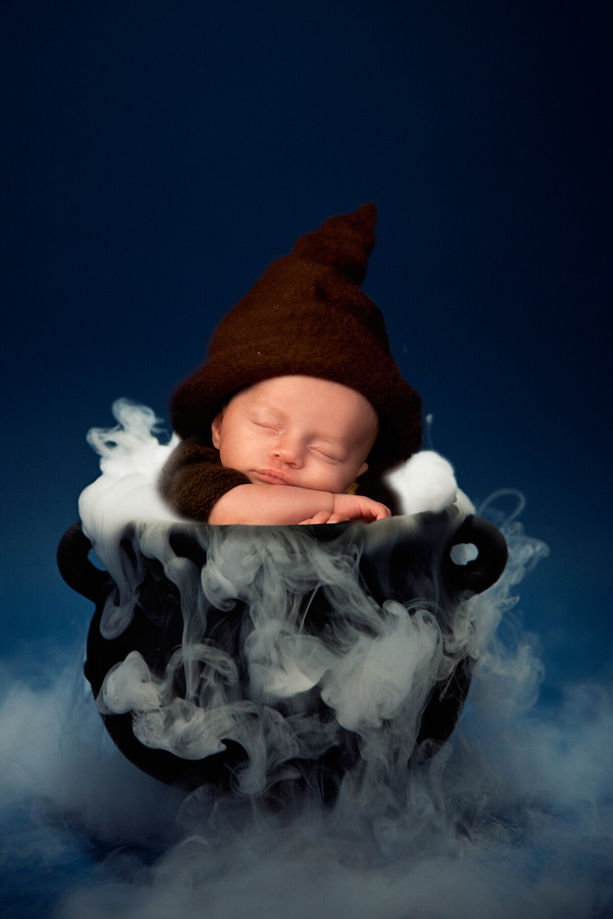 Wizard and witch themed Halloween newborn portrait featuring a cauldron and smoke , captured in Overland Park, Kansas. Perfect for families looking for whimsical and themed newborn photography in the Kansas City area