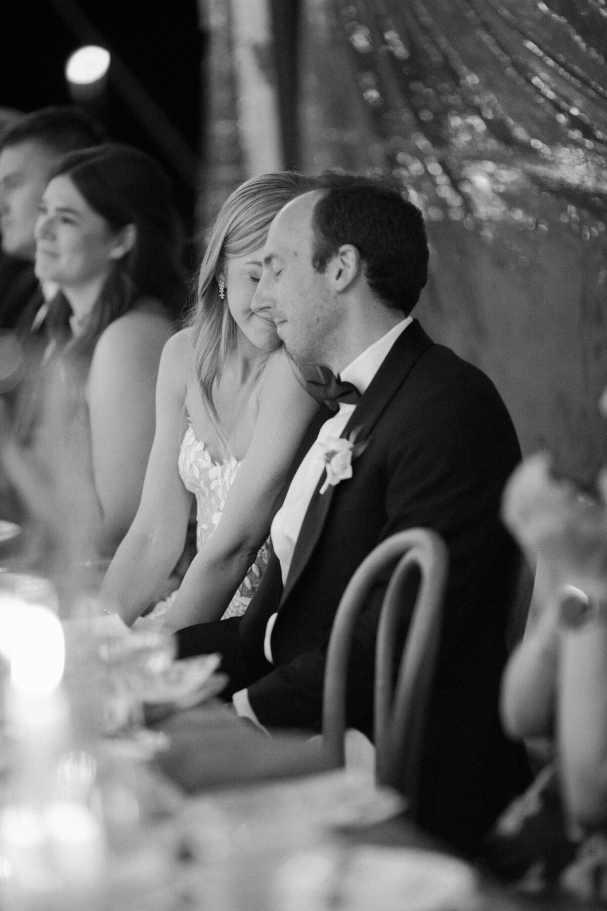 Bride leans into groom during wedding reception