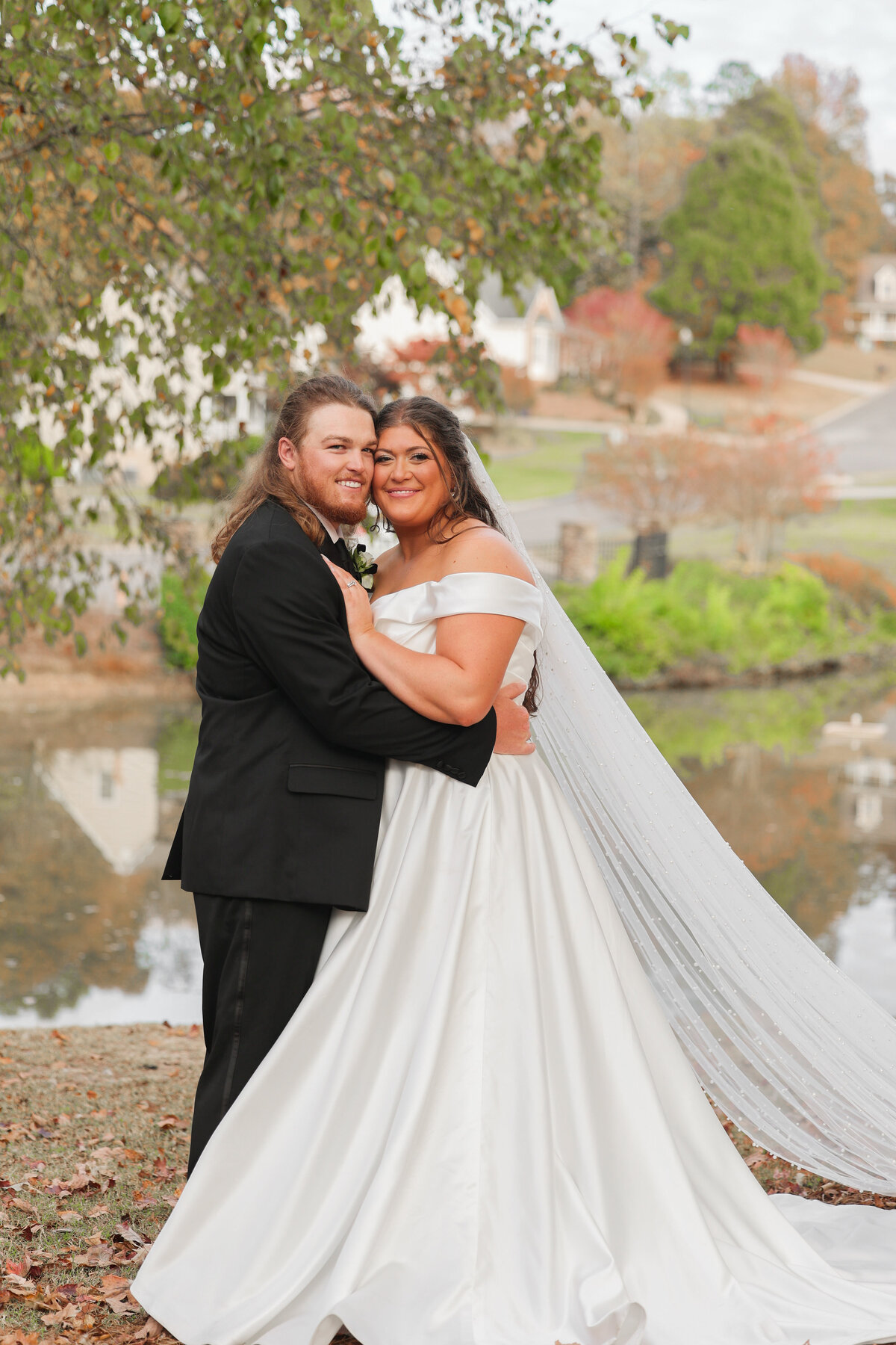 bride and groom holding each other wearing white silk dress and black tuxedo in Tennessee