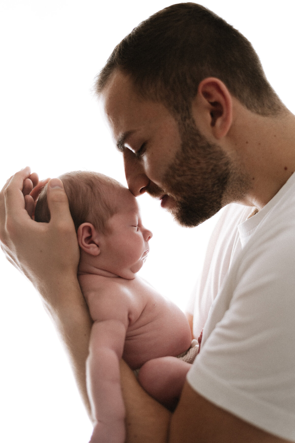 newborn baby being held up to his fathers nose at west sussex newborn photoshoot