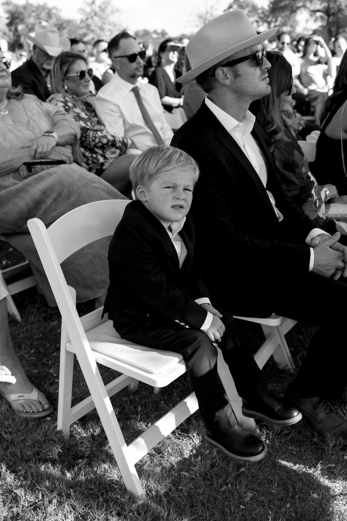 A little boy during the ceremony sitting down starring right at the camera. 