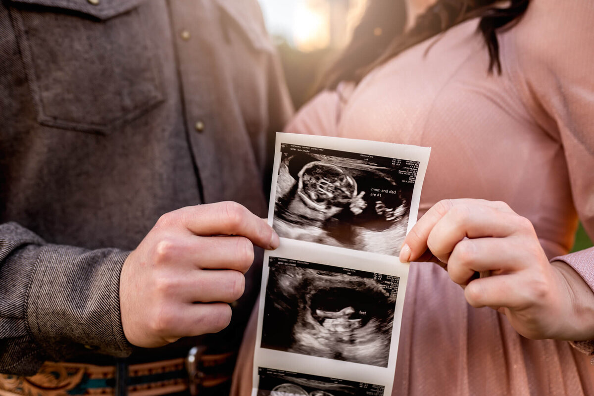 An expecting couple holds their sonogram photos