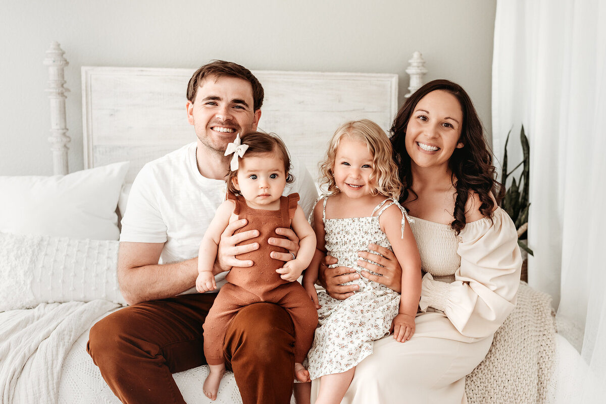 family of four sitting on daybed at milestone photo session