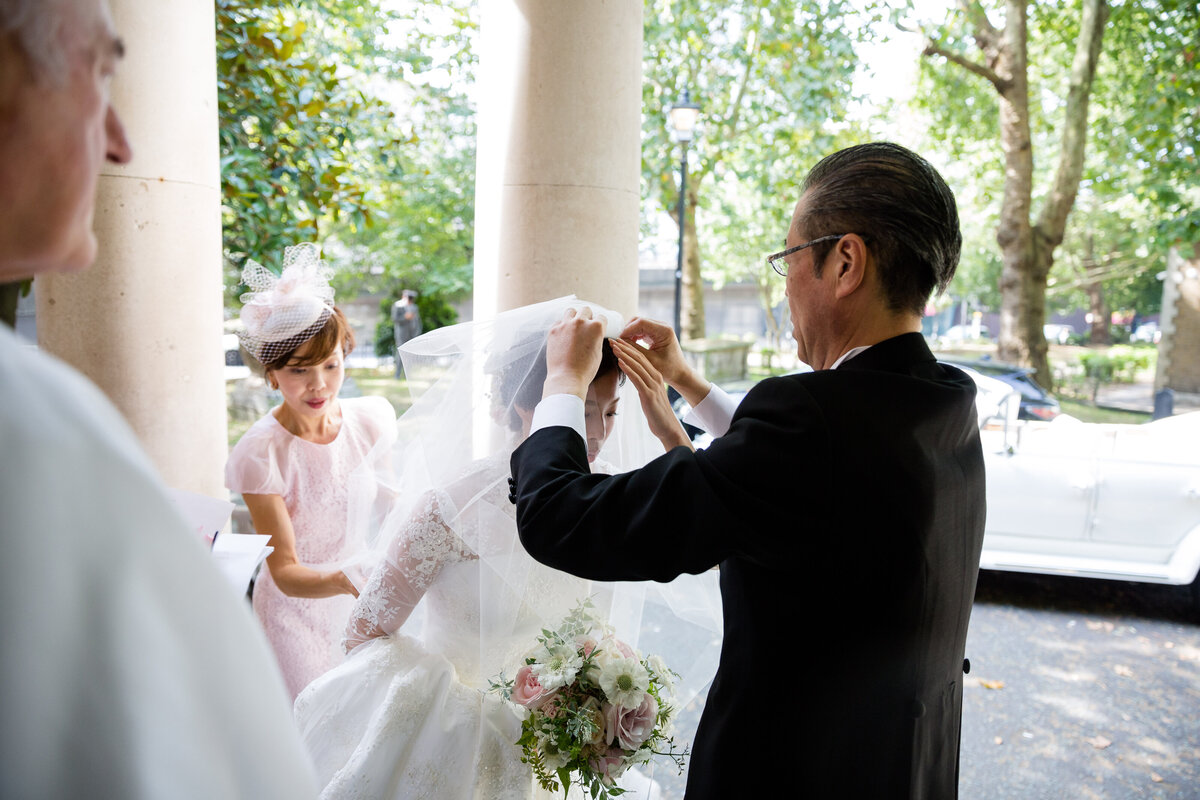 Bride putting her veil in her hair outside the church
