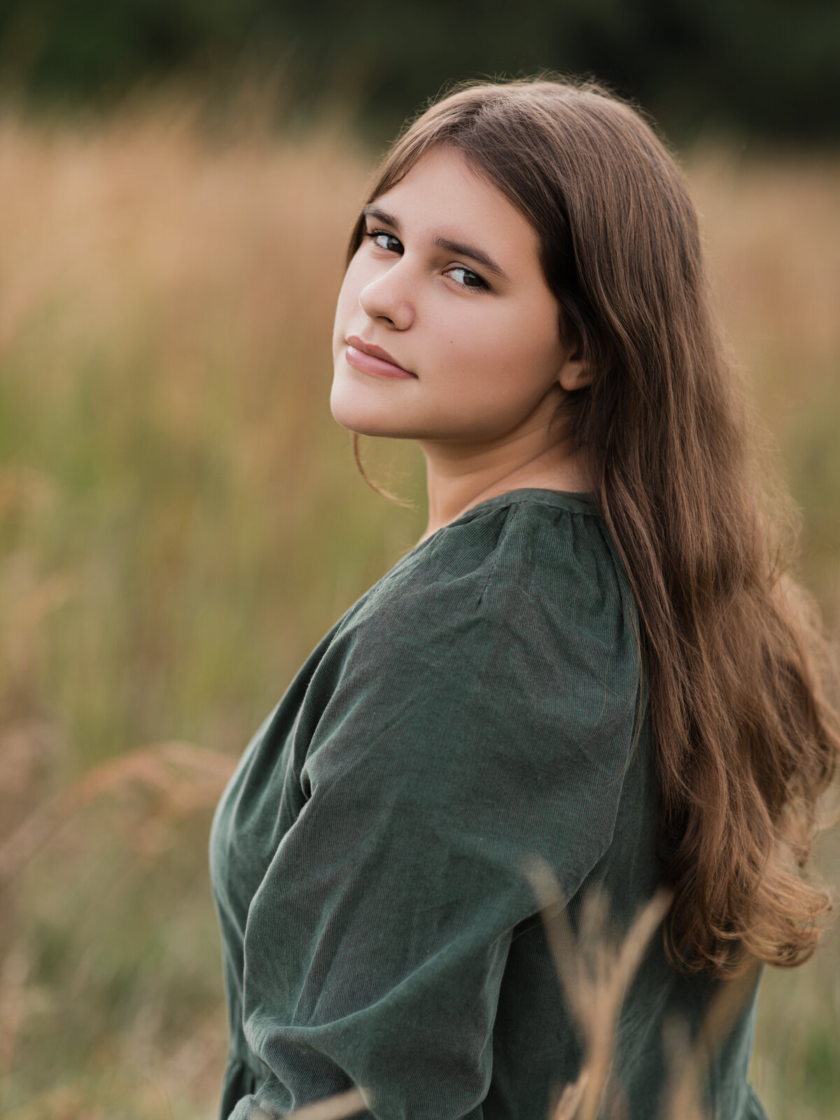 girl in green dress posing for family photoshoot in field