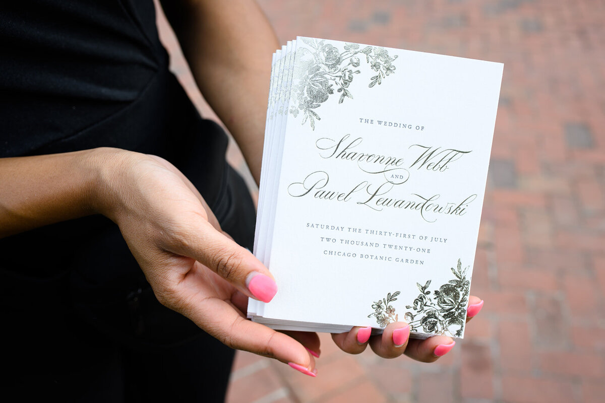 Close-up of a wedding program held by a guest.
