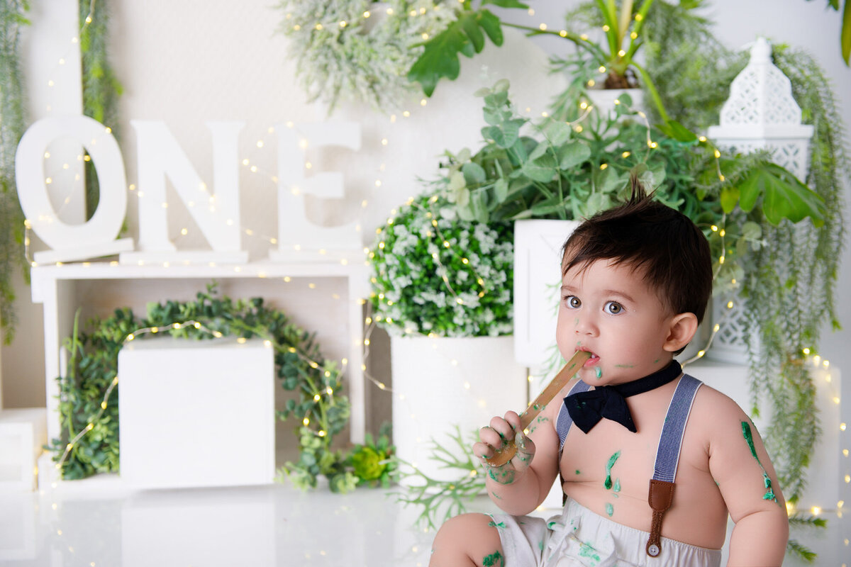 little boy with bow tie and suspenders having fun with his first year photoshoot