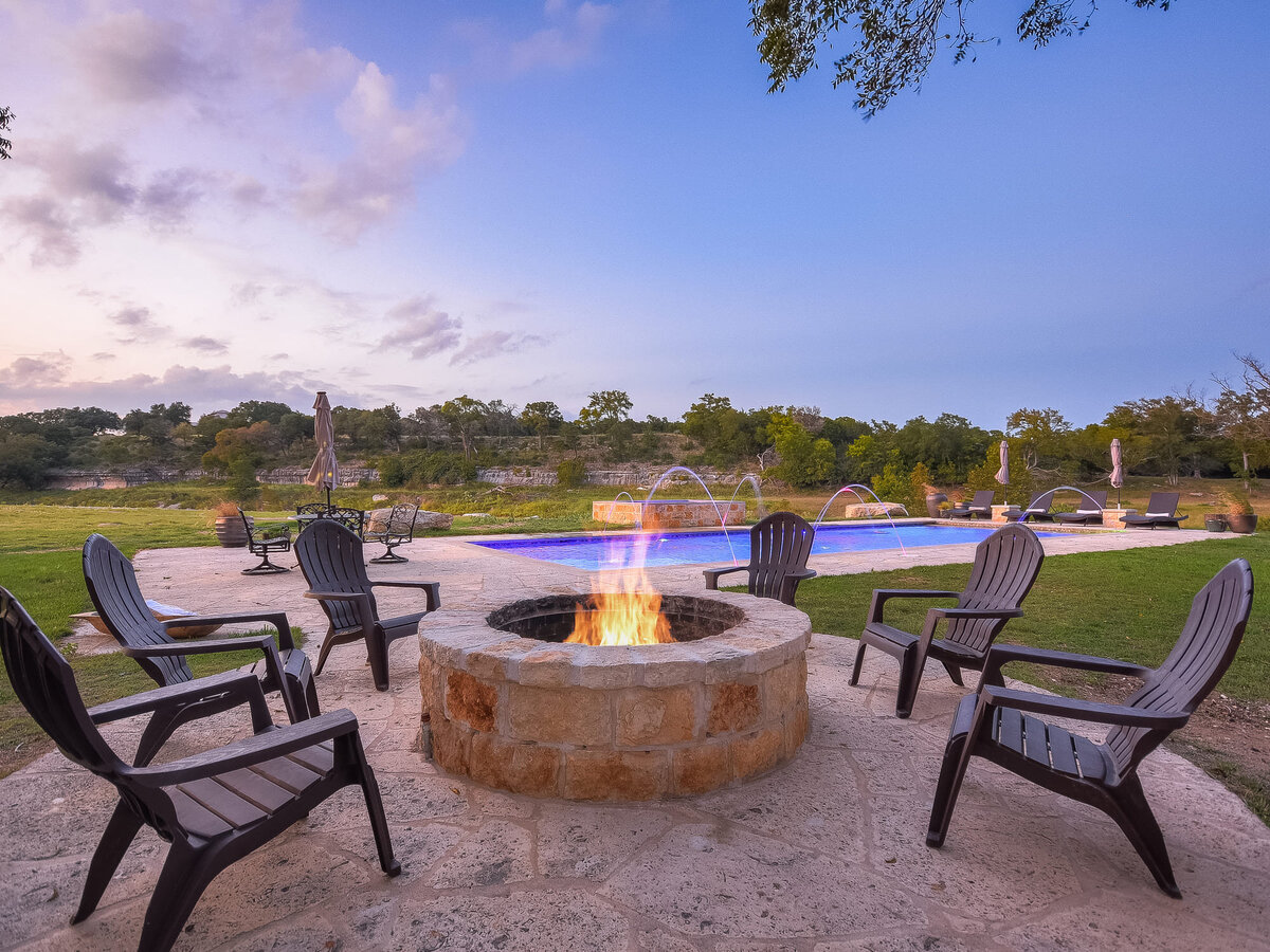 Exterior firepit patio with pool in background