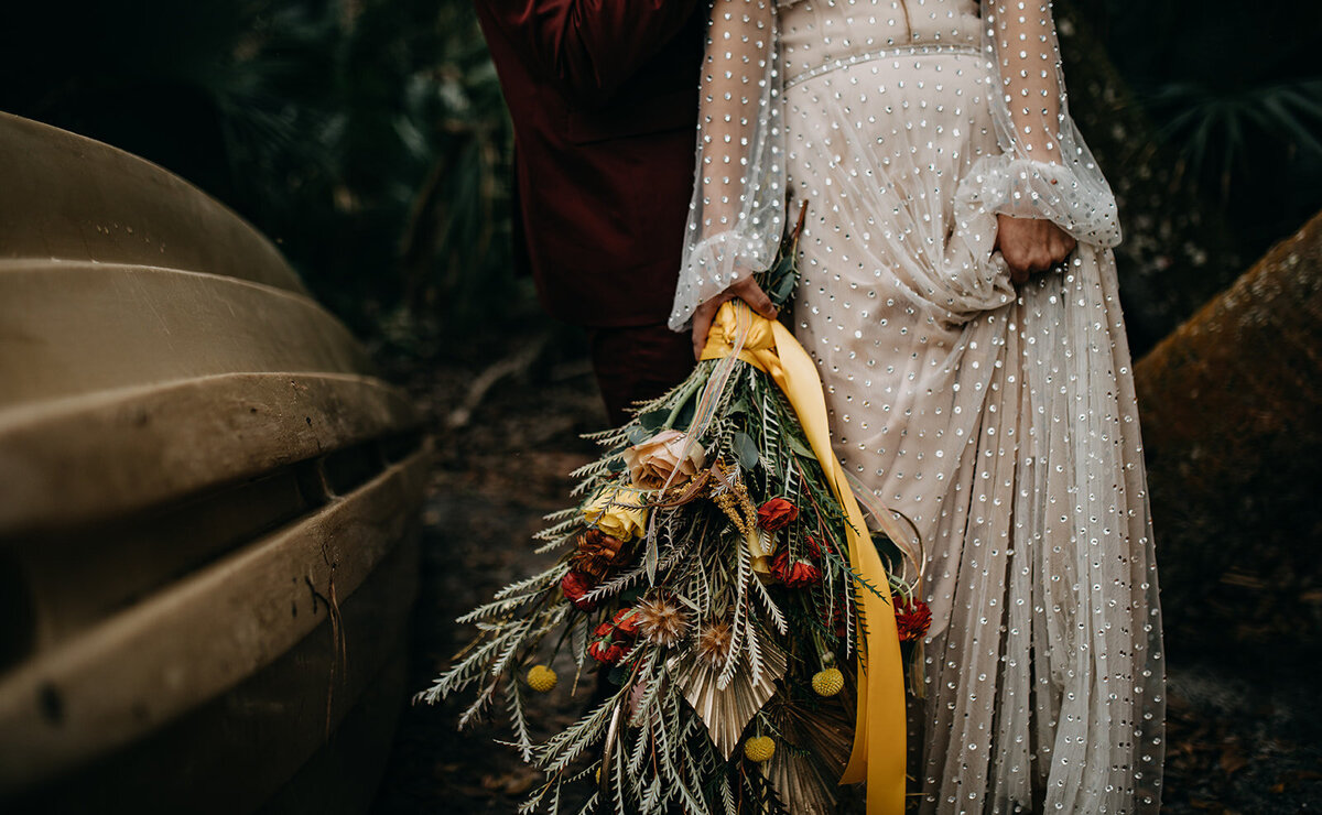 woman holds up dress and bouquet