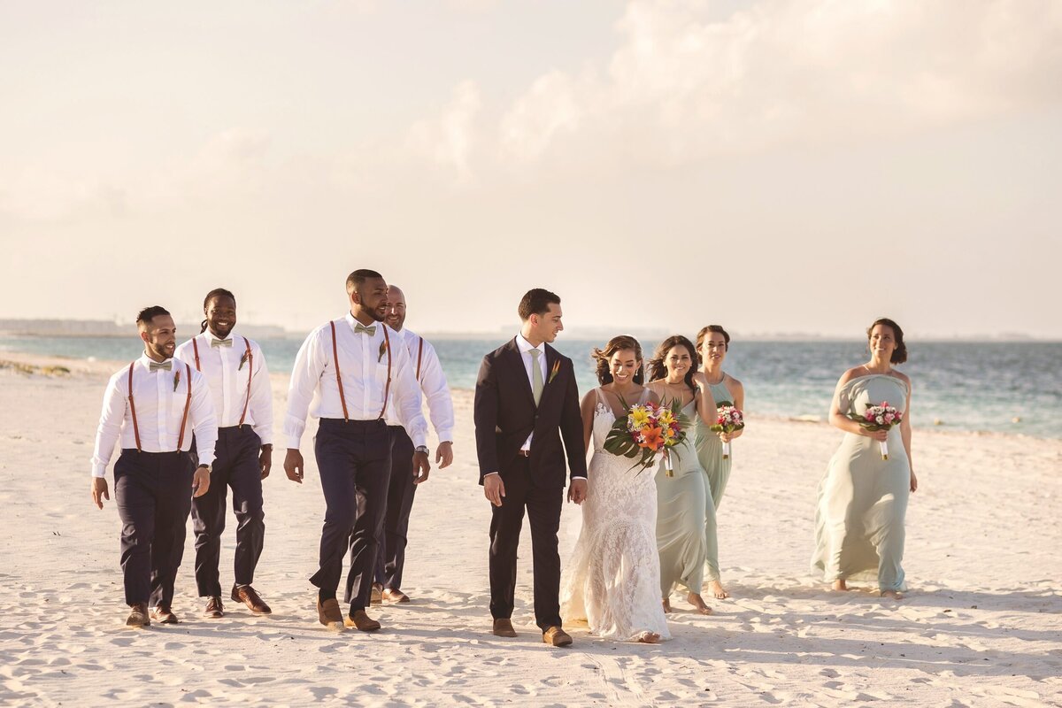 Bridal party walking on beach together after wedding in Cancun