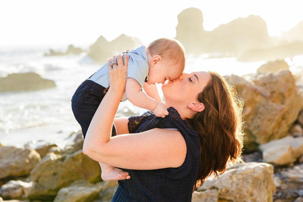 mom kisses baby on beach