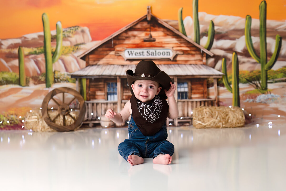 One year old Tampa baby enjoying a personalized luxury cake smash session with playful Wild West decorations
