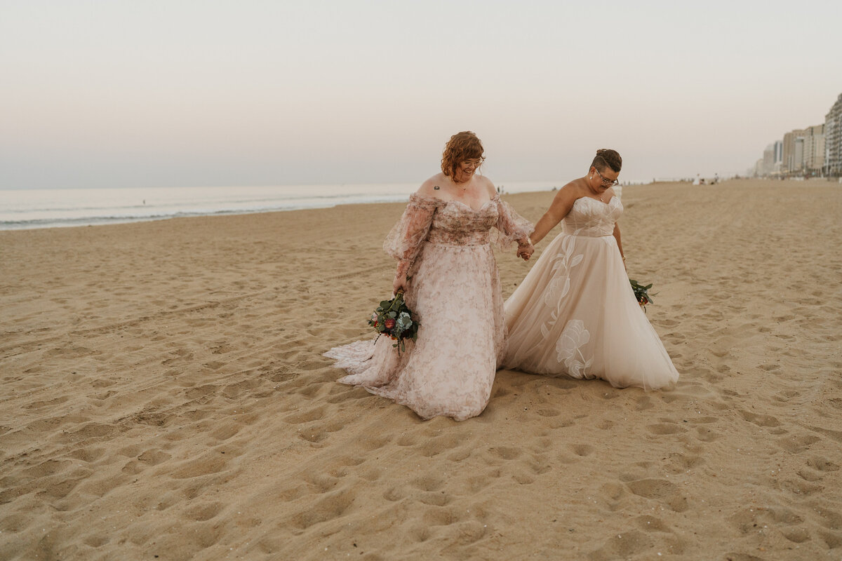 A newlywed couple holding hands and walking on the beach 