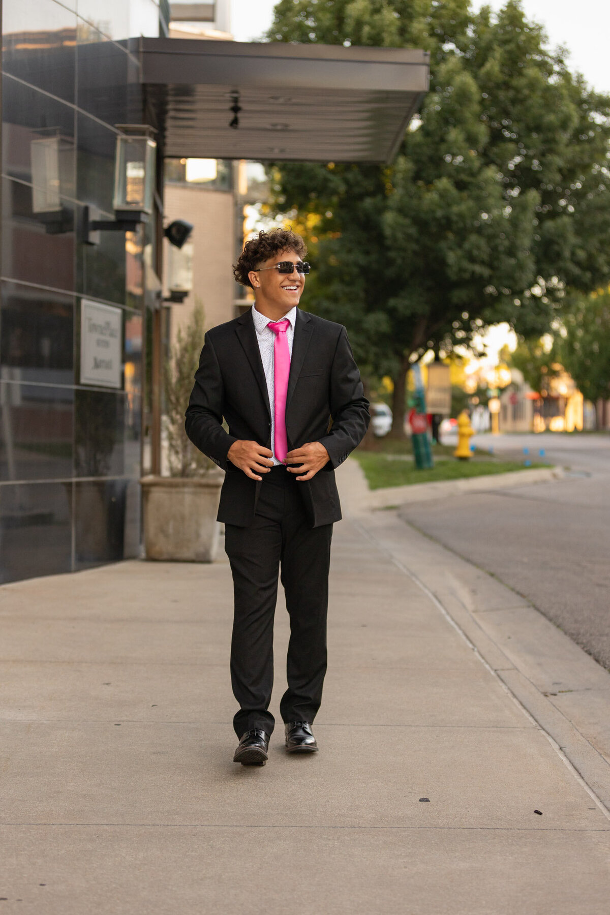 A senior guy walking in a suite looking off camera smiling in Lawrence, KS