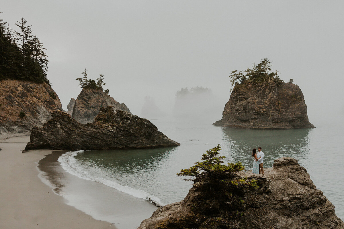 A couple in wedding attire running on an Oregon Coast beach during their elopement