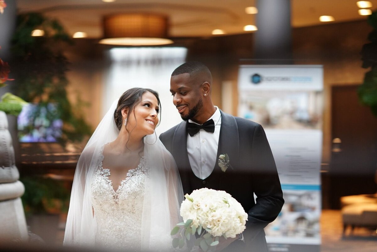 A couple walks hand in hand through a stylish, modern interior with sleek furnishings and contemporary decor. The image highlights their elegance and the sophisticated ambiance of the setting.