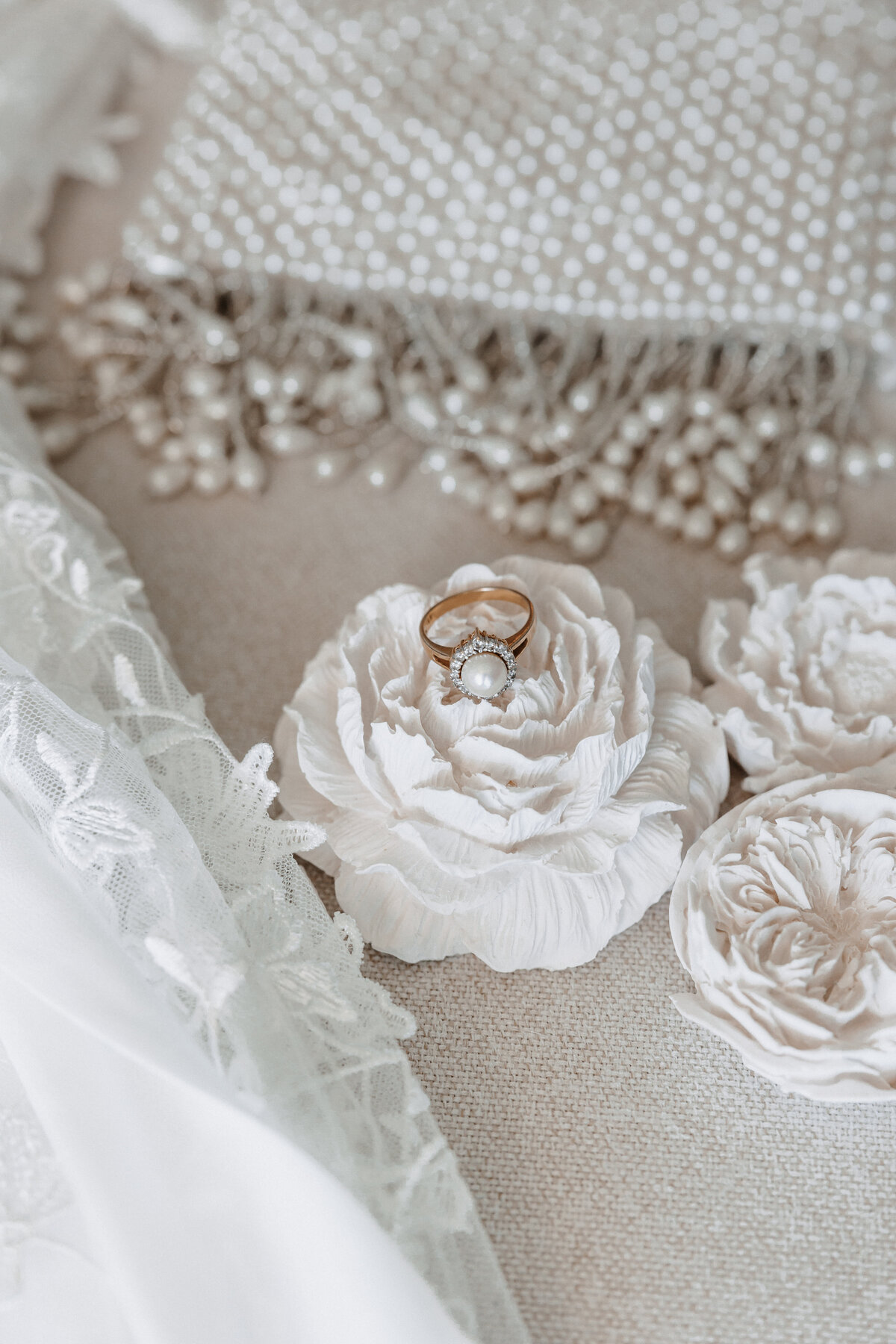 Wedding ring on top of cermamic flower with pearls and lace