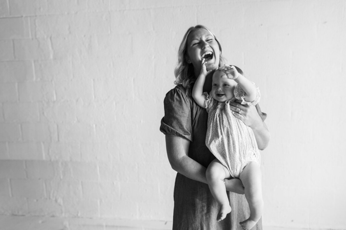 a mom laughing while holding her toddler