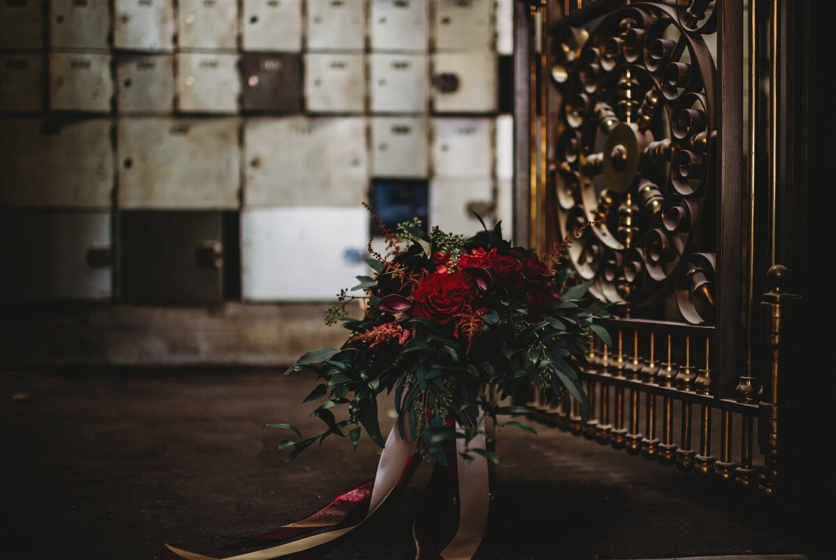 Detail shot of brides wedding bouquet sitting on the floor with a gold door to the right and other rustic details in the distance photographed by Maryland wedding photographer