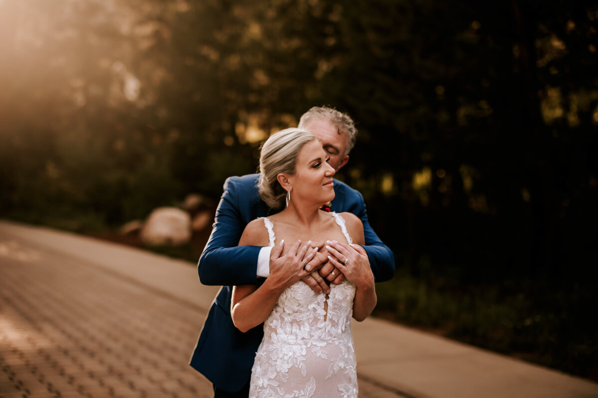 Husband embracing his new wife from behind during golden hour at Della Terra in June