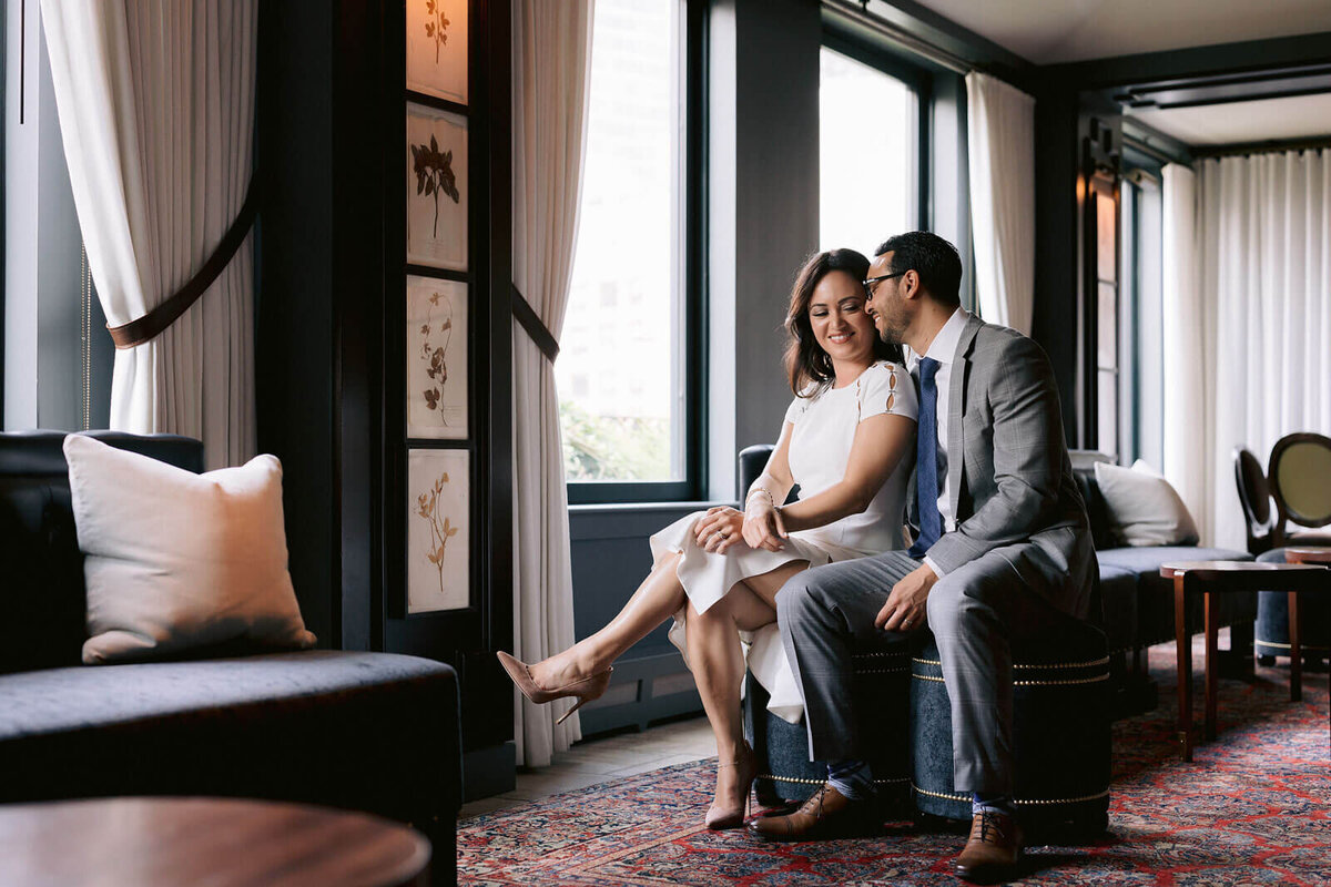 The bride and groom are happily sitting inside a hotel room in New York City. Image by Jenny Fu Studio