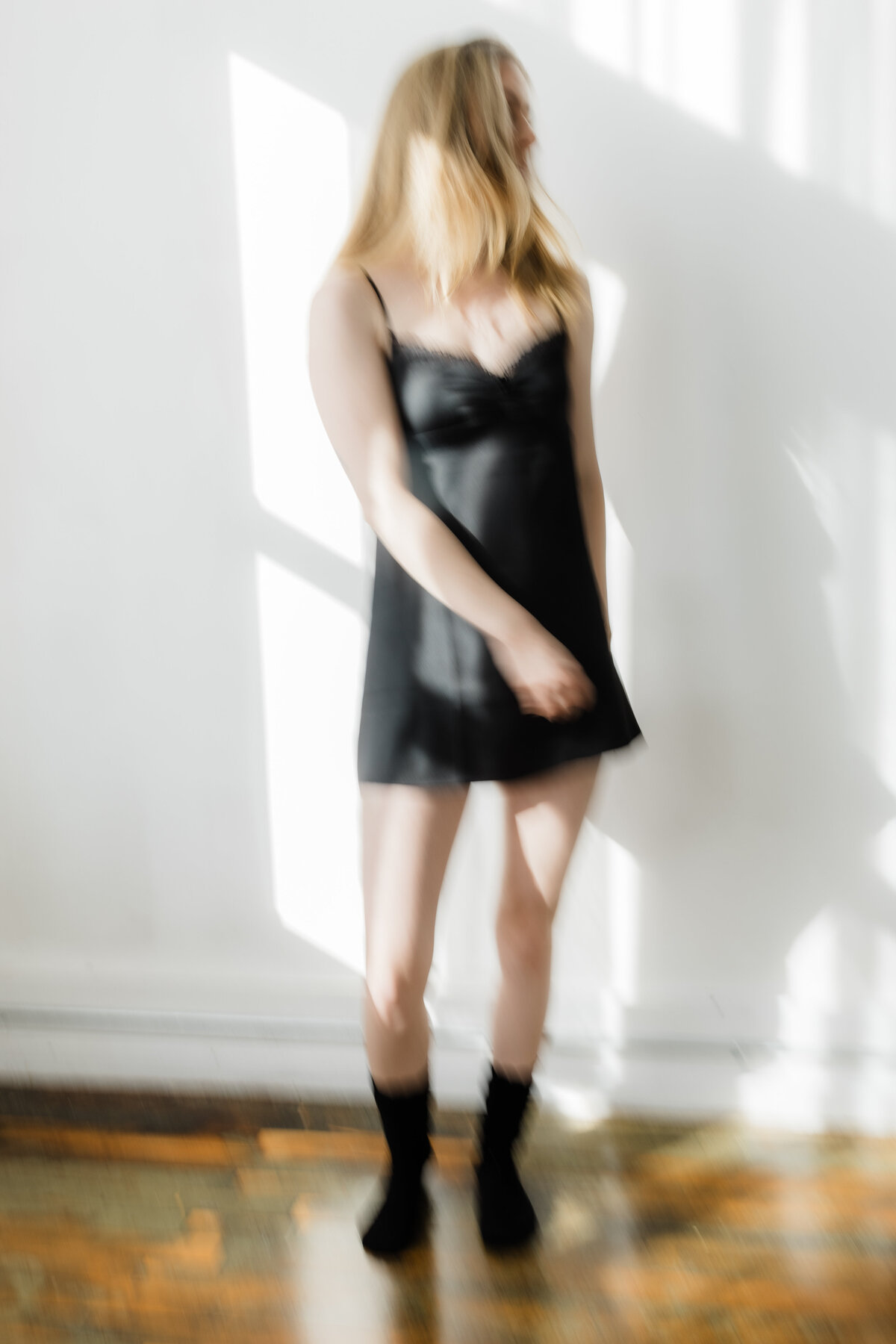 Woman posing in a black slip dress in a naturally lit room during a South Bend boudoir session.