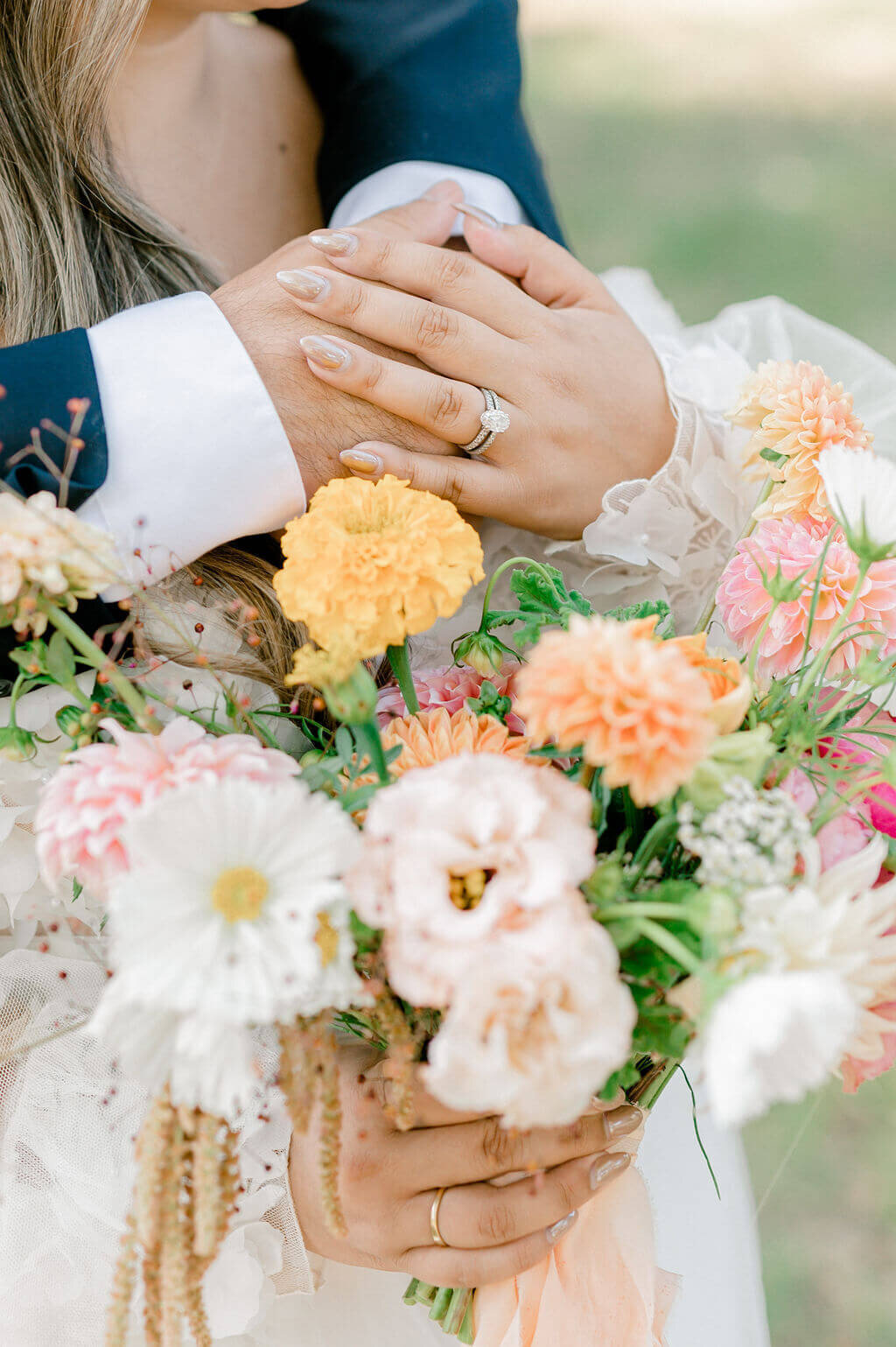 close up of bride and grooms hands with the colorful bouquet