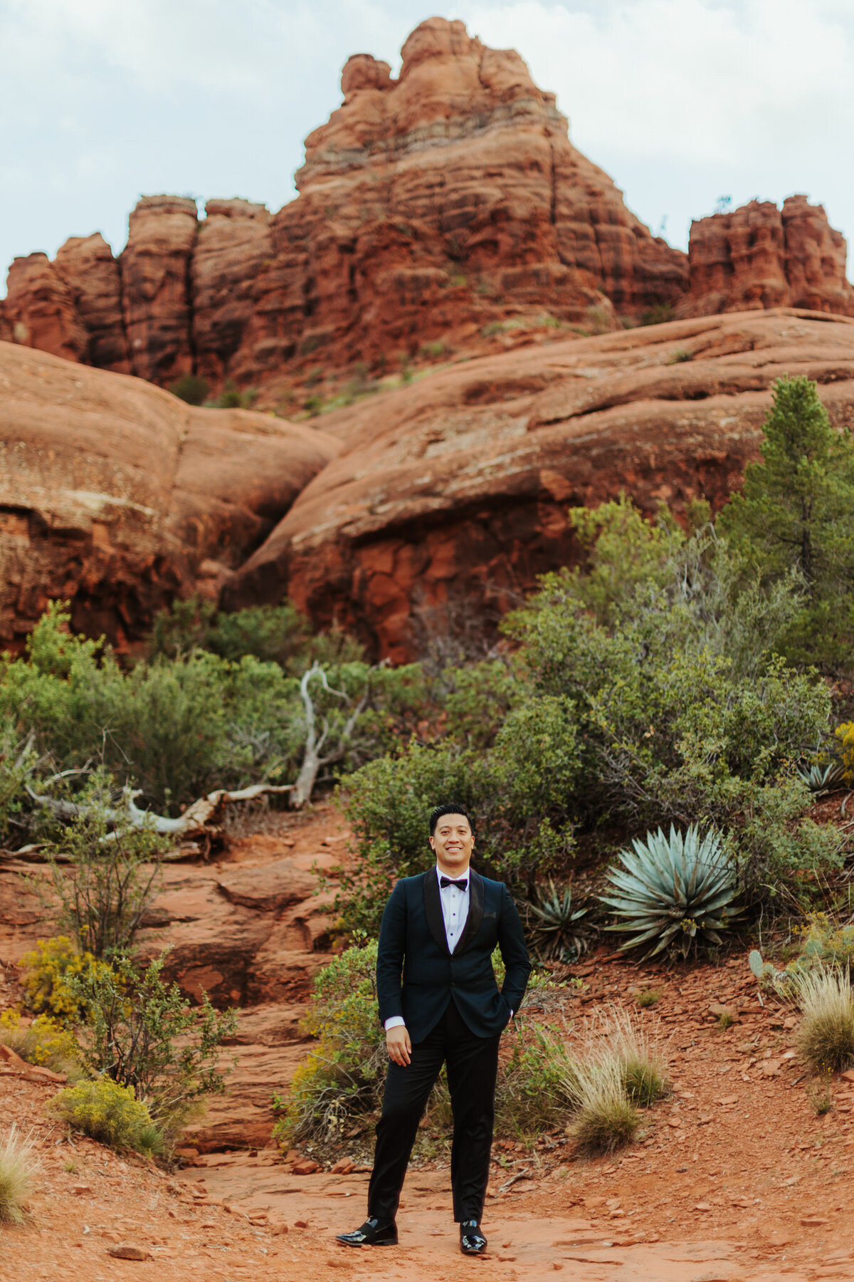 groom stand sin front of bell rock for wedding photo