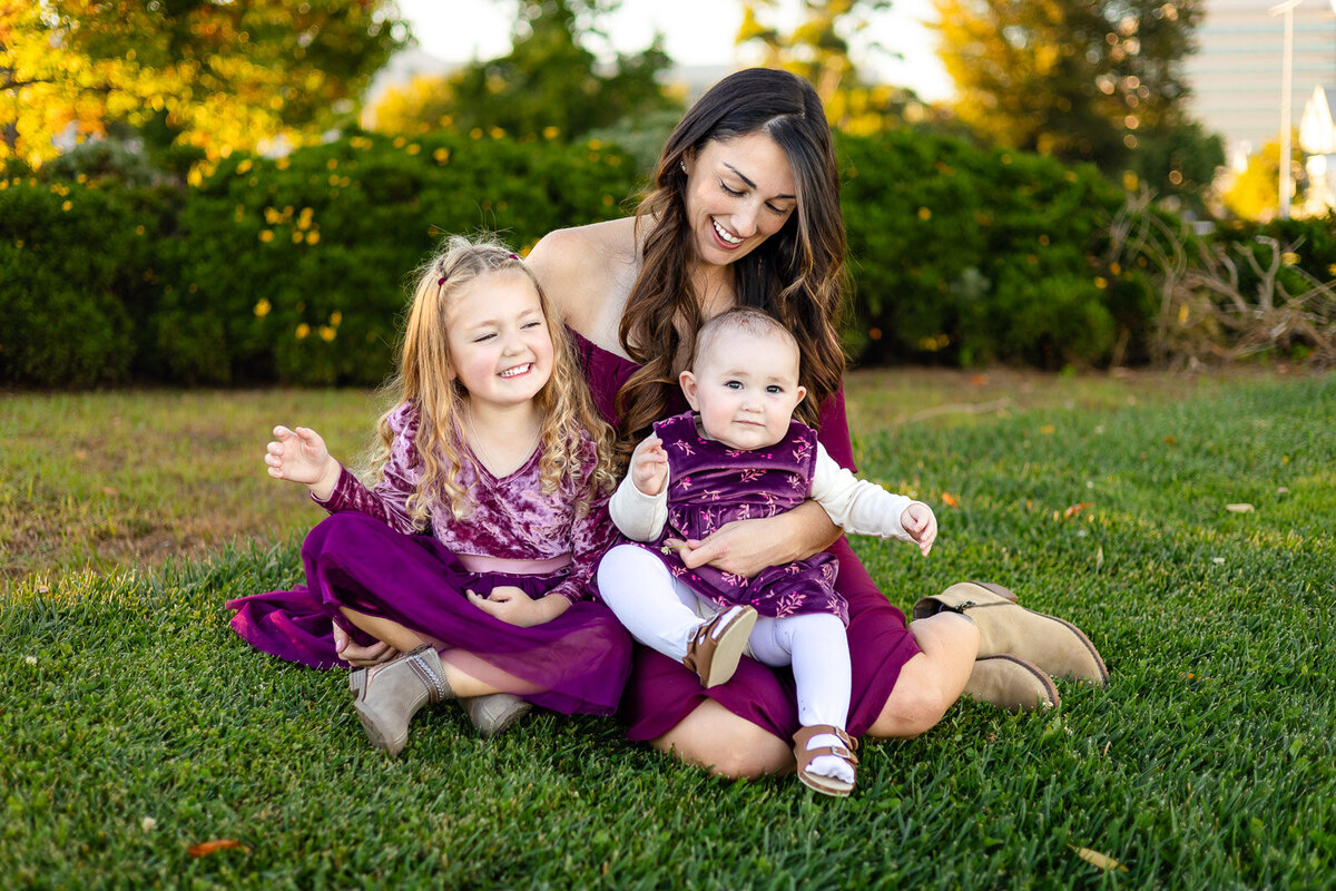 Mother and daughters sharing smiles in matching plum outfits at a Bay Area park – Bay Area Family Portfolio – Ellobelle Photography
