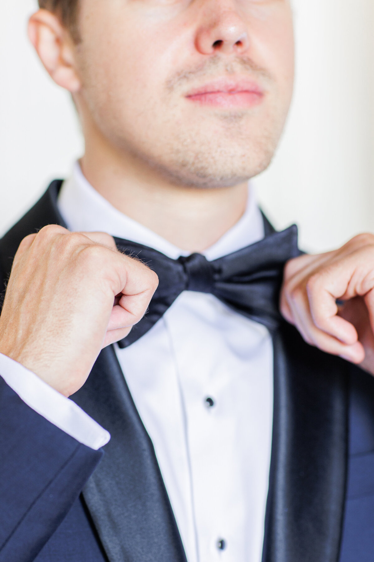Close up of groom adjusting his bow tie
