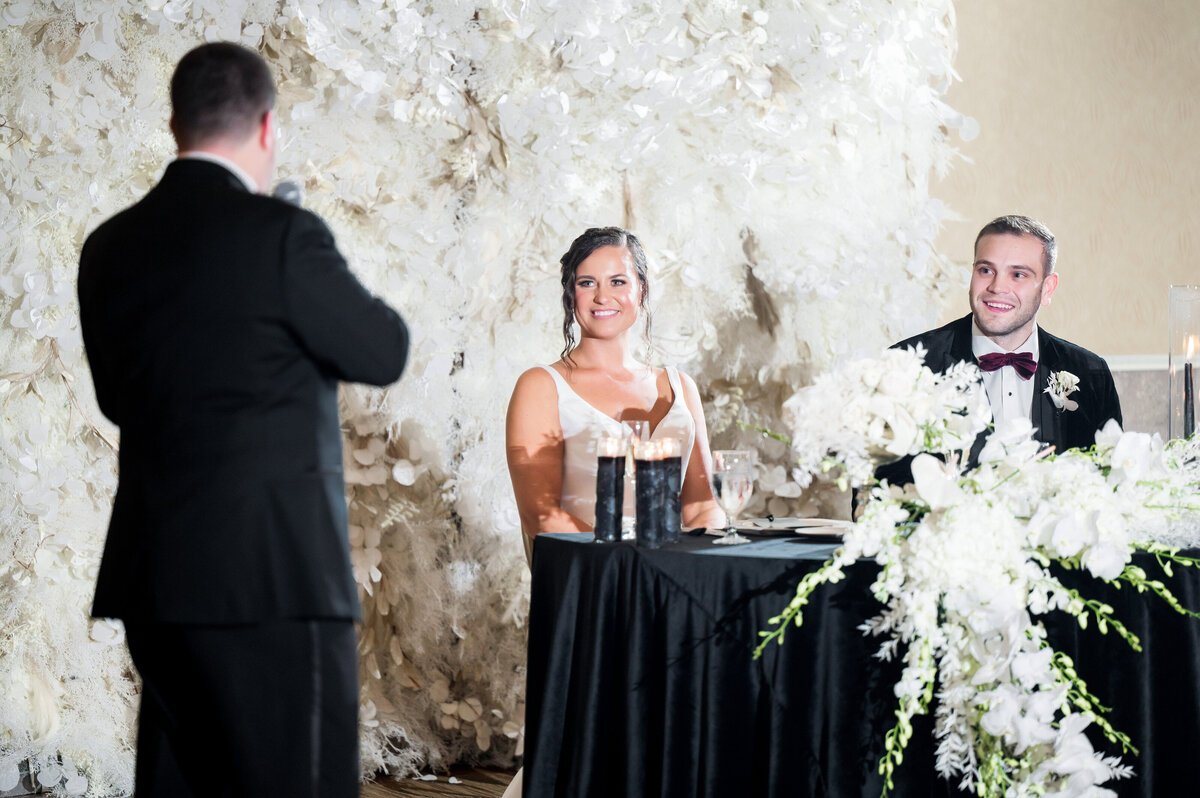 bride listening to a wedding toast at her reception 