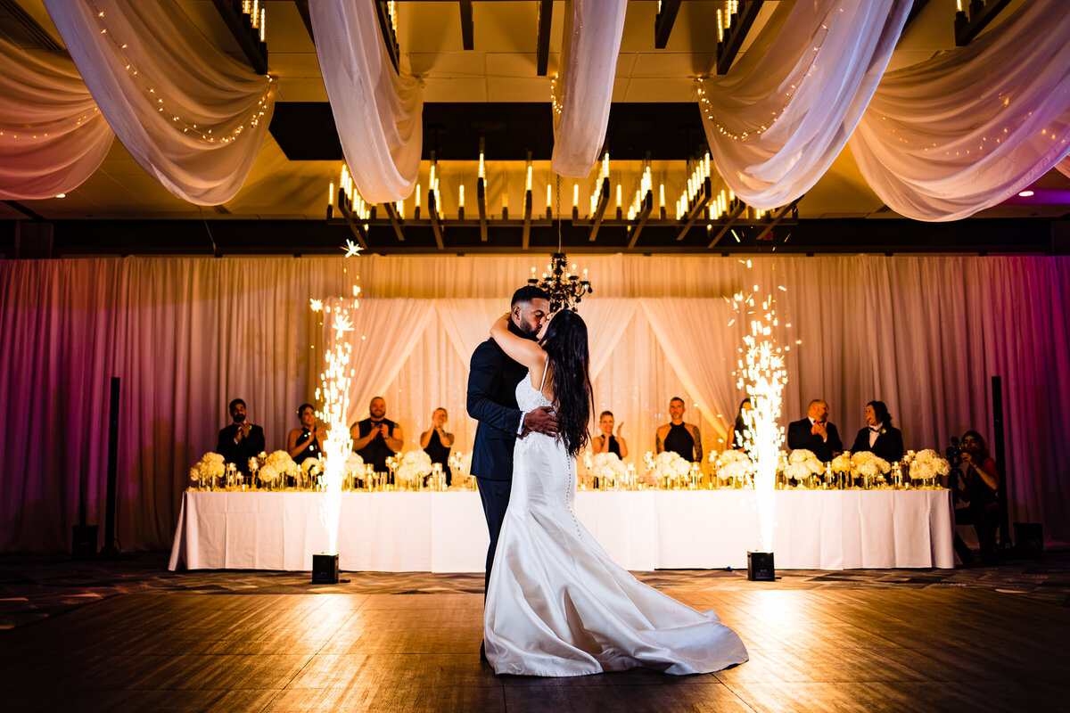 One of the top wedding photos of 2021. Taken by Adore Wedding Photography- Toledo, Ohio Wedding Photographers. This photo is of a bride and groom kissing during the first dance as sparklers light behind them.
