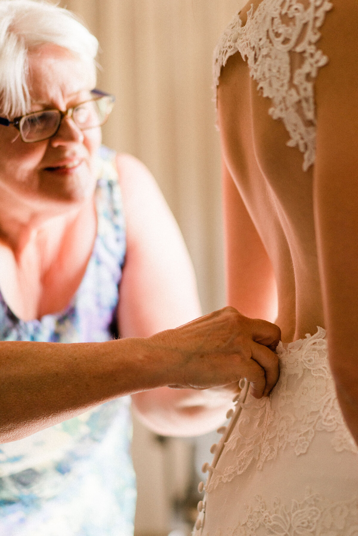 Mom helps bride into wedding dress inside UW Center for Urban Horticulture wedding venue at Wistiria Hall