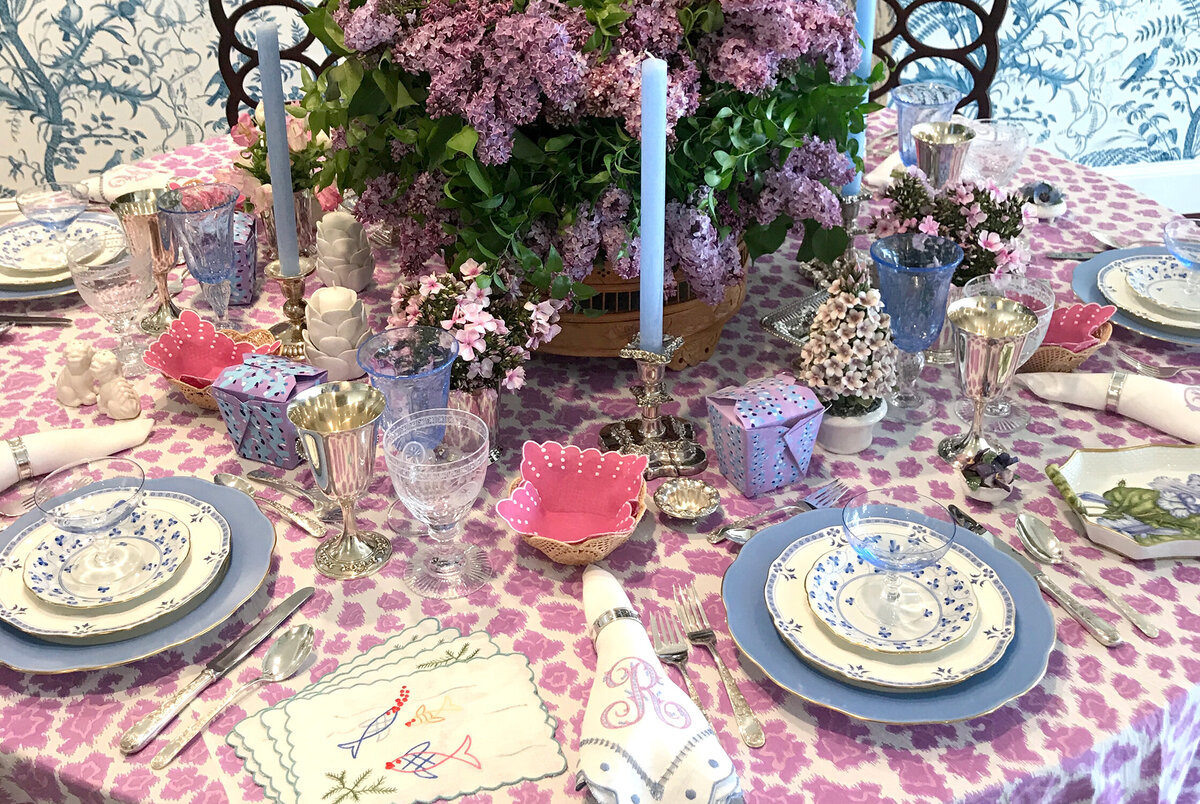 Whimsical, layered tablescape featuring lilacs, taper candles, pink leopard table cloth and custom embroidered napkins