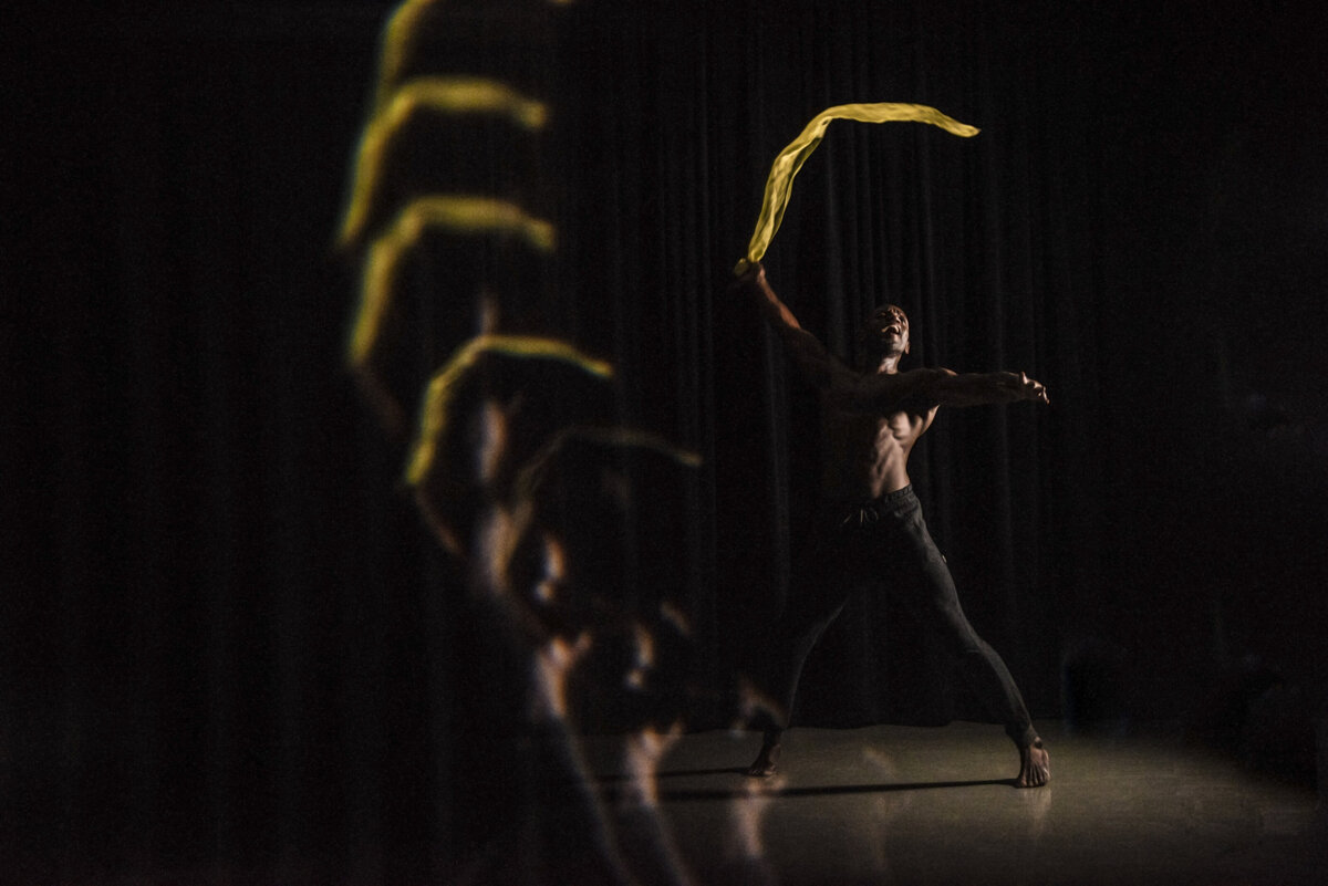 A person dancing with a yellow cloth with the reflection in front of them