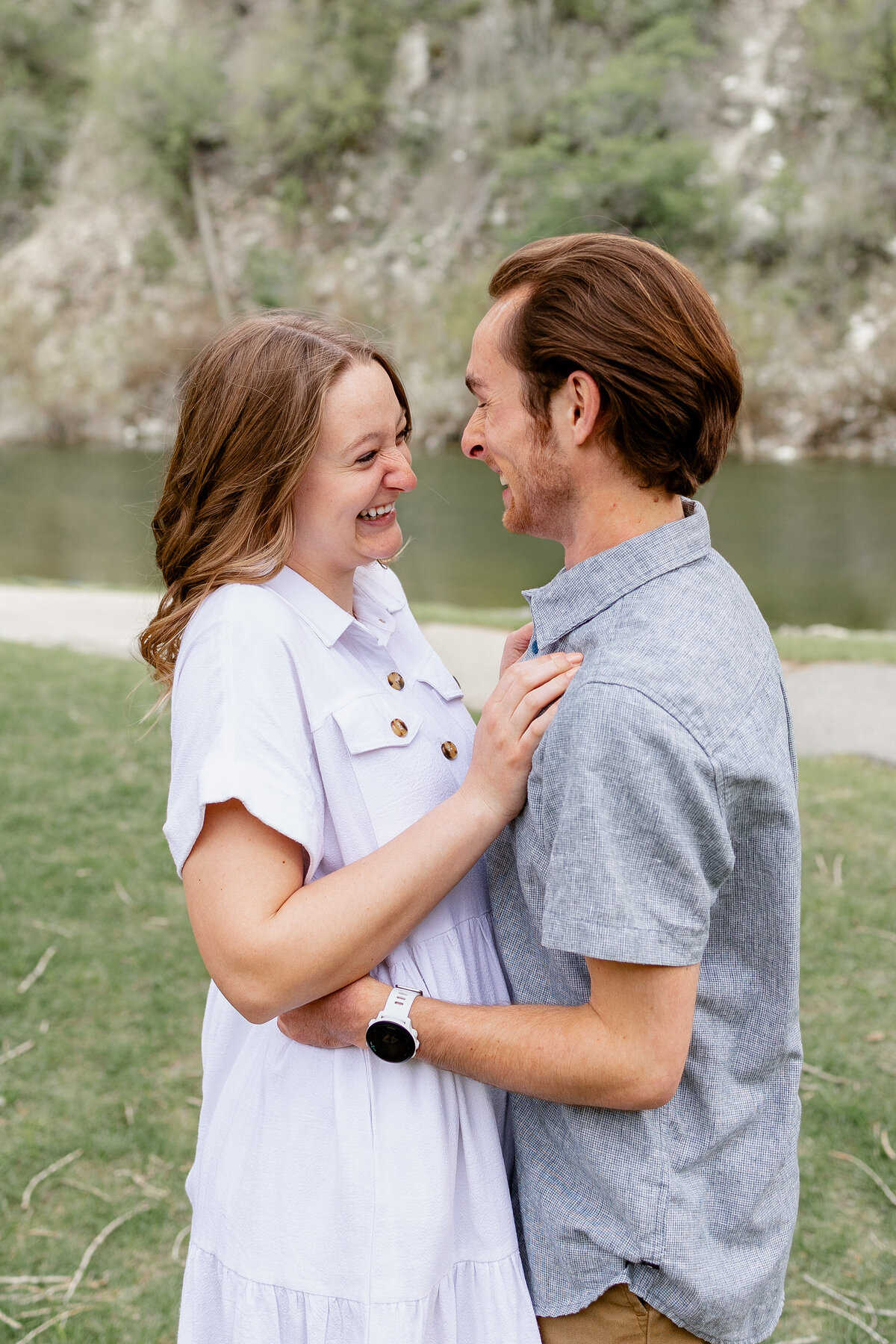 A couple stands by the river, gazing into each other's eyes with joy and love in their expressions, surrounded by nature’s beauty in Provo Canyon.